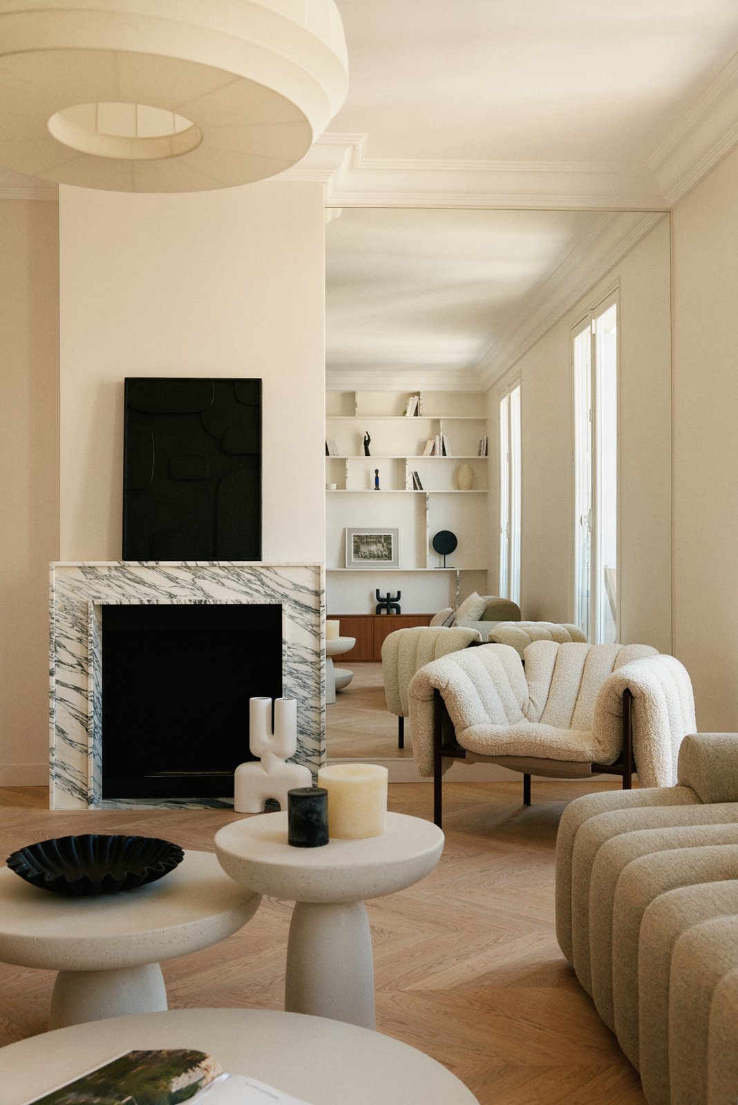 A living room with a marble fireplace and cream armchairs.
